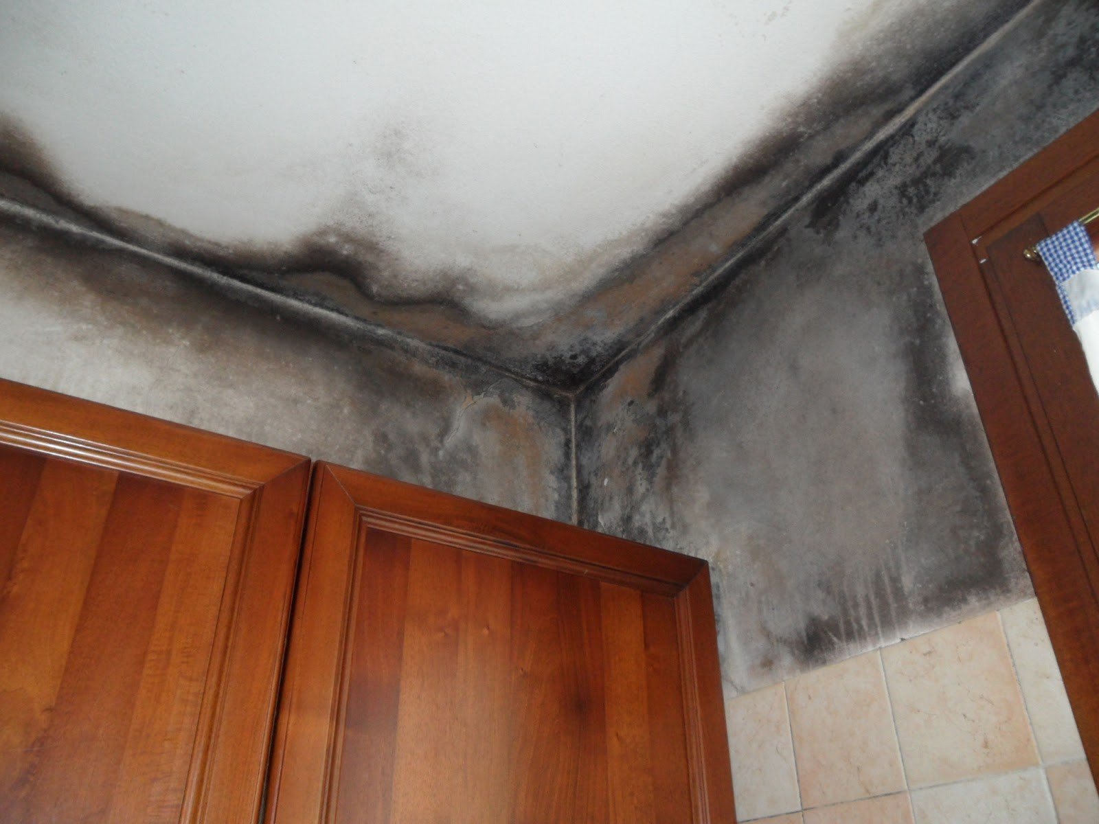 Stanza con muro rovinato dall'umidità, mobile e finestra in legno